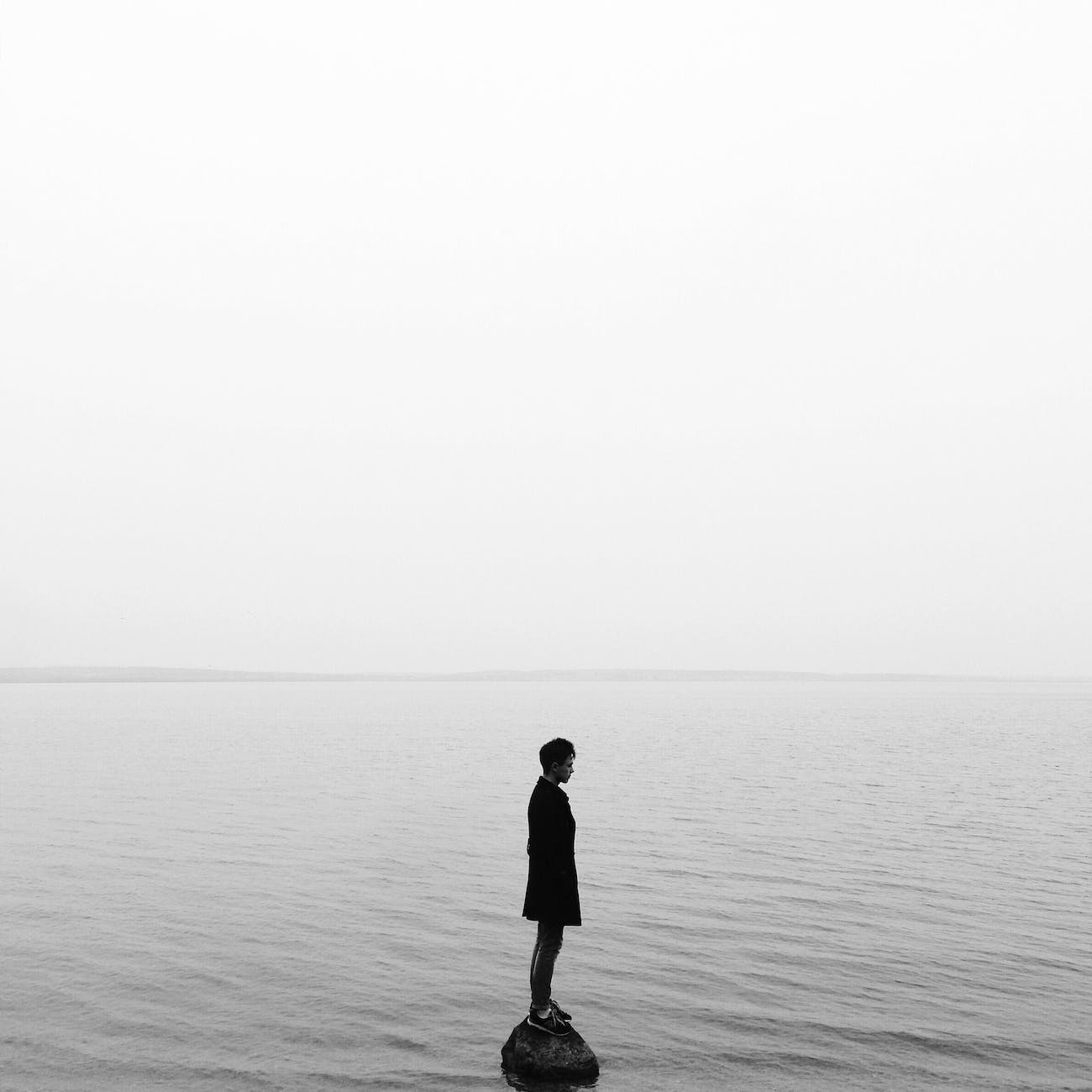 man in black jacket standing on the seashore